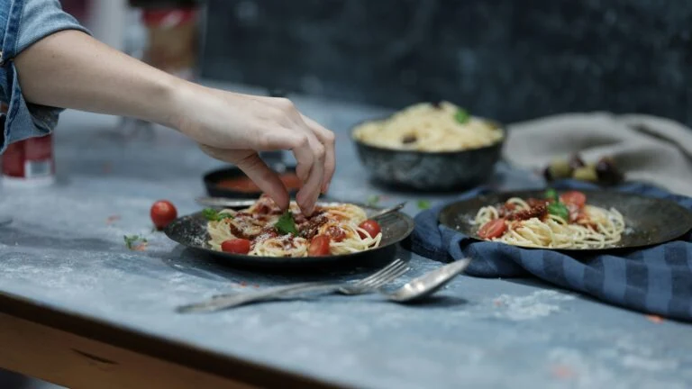 Chef adding the finishing touches on a plate of spaghetti