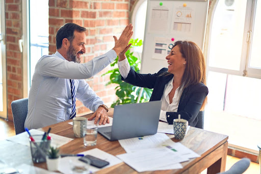 A man and a woman high fiving each other in a business.